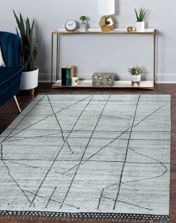 Light gray textured rug with black geometric lines lays on a dark wood floor near a gold console.