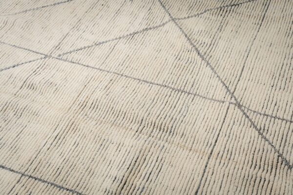 High-pile ivory rug featuring vertical textured rows and a sparse geometric pattern of thin gray lines.