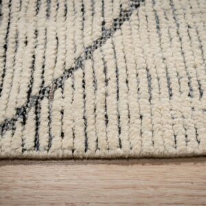 Creamy high-pile rug detail showing chunky texture and dark gray geometric stripes on light wood.
