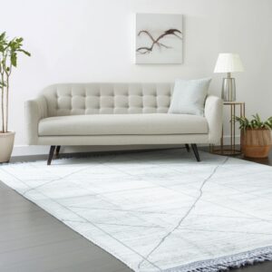 Light white rug with gray diagonal lines under a beige tufted sofa on dark wood flooring.