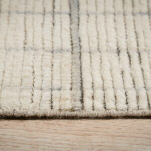 High-pile cream rug with a gray grid pattern and chunky texture resting on light wood flooring.