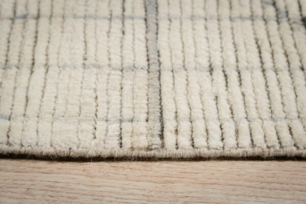 High-pile cream rug with a gray grid pattern and chunky texture resting on light wood flooring.