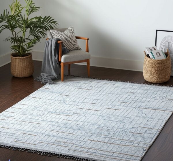 A light gray flat-weave rug with a blue grid pattern and tan accents rests on dark wood flooring.