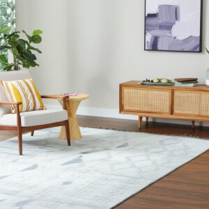 Light gray low-pile rug with geometric patterns sits beneath an armchair and wood console table.