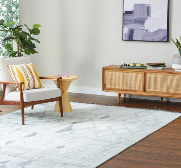 Light gray low-pile rug with geometric patterns sits beneath an armchair and wood console table.