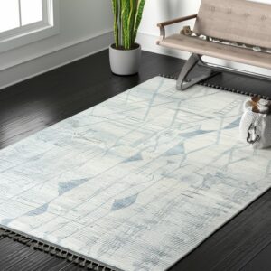 Light blue and white geometric rug with dark tassels contrasts with the black wood floor and tan bench.