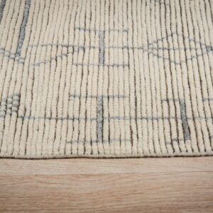 Close view of a cream, high-pile rug with a gray geometric pattern resting on light wood floor.