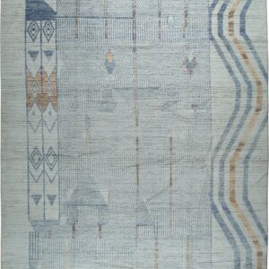 Textured light blue rug with geometric block patterns and diagonal rust and navy stripes and tassels.