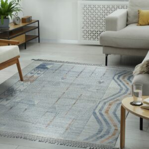 Geometric gray, blue, and tan rug on light wood flooring between a sofa and an accent chair.