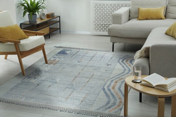 Geometric gray, blue, and tan rug on light wood flooring between a sofa and an accent chair.