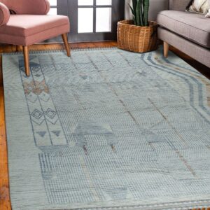 Light blue flatweave rug with indigo and tan geometric patterns anchors a living area with wood floors.