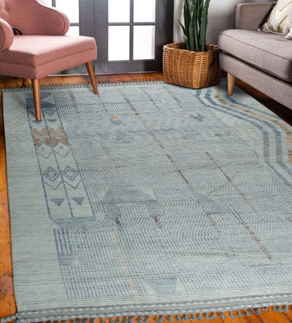 Light blue flatweave rug with indigo and tan geometric patterns anchors a living area with wood floors.