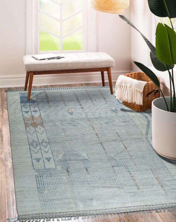 Light blue geometric rug with tan accents rests on wood flooring near a bench and window.