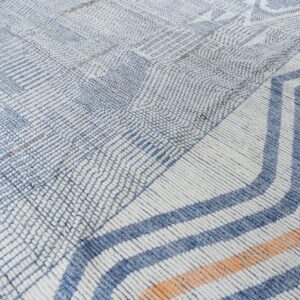 Cream and blue textured rug with geometric designs transitioning to thick orange and blue chevrons.