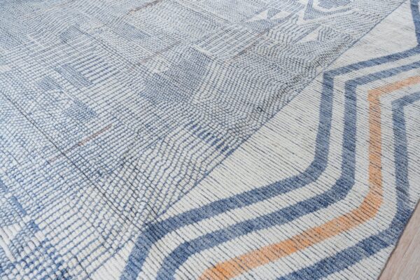 Cream and blue textured rug with geometric designs transitioning to thick orange and blue chevrons.