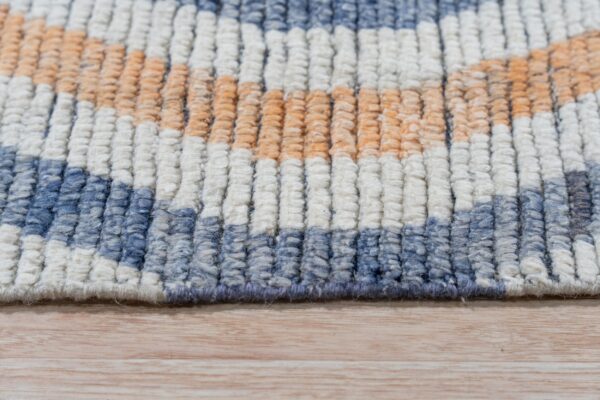 High pile rug detail showing textured rows of blue, cream, and orange on light wood flooring.