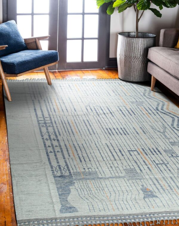 White and blue abstract rug with orange lines rests on hardwood floors near a blue chair.