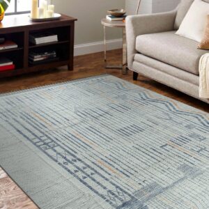 Textured gray-blue rug featuring repeating vertical blue stripes and orange accents on hardwood flooring near a sofa.