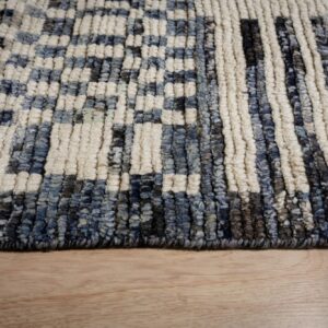 Textured navy, gray, and cream high-pile rug with a checkered pattern resting on light hardwood.