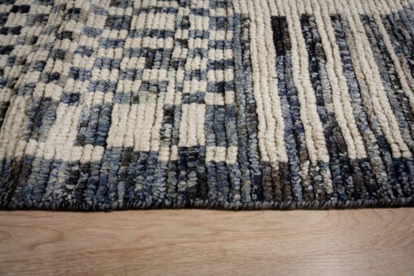 Textured navy, gray, and cream high-pile rug with a checkered pattern resting on light hardwood.