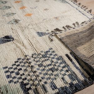 High-pile cream rug with blue and orange shapes folded over to expose the striped woven backing.