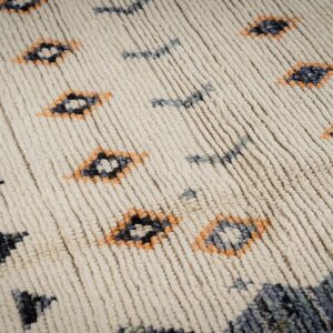 Textured cream rug with high pile and abstract patterns in dark blue, gray, and orange.