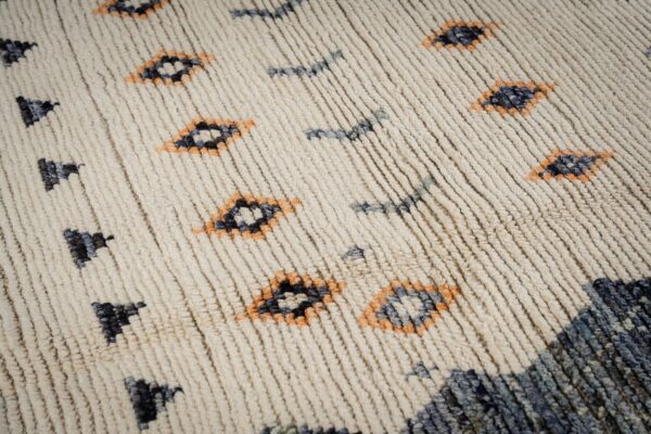 Textured cream rug with high pile and abstract patterns in dark blue, gray, and orange.