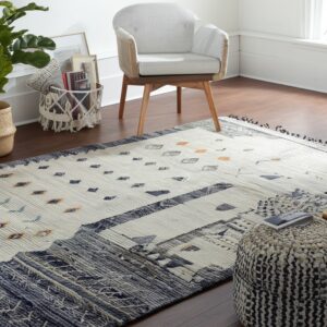 A textured cream flatweave rug with navy and rust geometric patterns covers a dark wood floor.