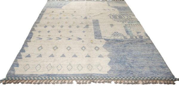 Abstract high-pile rug in cream and shades of blue with geometric elements and thick gray-taupe fringe.