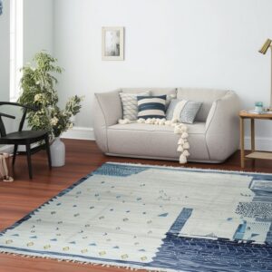 Abstract blue, gray, and yellow low-pile rug lying on wood flooring beneath a curved light sofa.