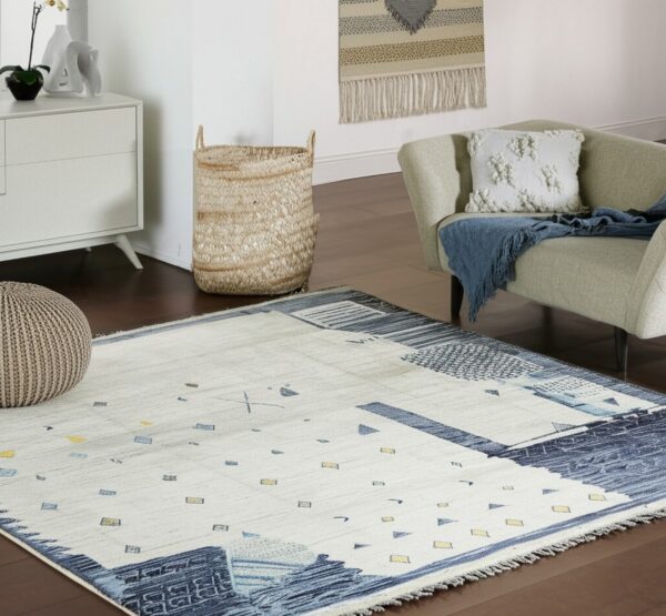 Abstract cream and indigo rug with scattered yellow geometric shapes anchors a room with wood floors and a chair.