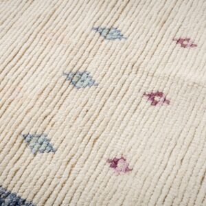 Ribbed high-pile cream rug texture features scattered small magenta and light blue abstract accents.