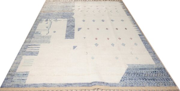 Shaggy cream rug with thick blue abstract patterns and small scattered pink and blue geometric accents.