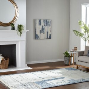Abstract blue and cream rug anchors a bright living room with a white fireplace and gray couch.