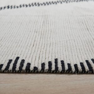 Cream high-pile rug on light wood flooring showing black dashed vertical stripes at the edge.