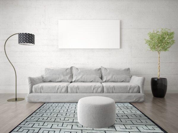 A geometric black and light blue patterned rug sits under a gray sofa and ottoman on wood flooring.