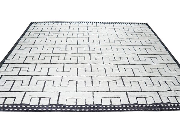 White textured rug featuring a bold repeating dark geometric meander pattern and a contrasting dark border.