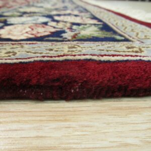 A thick, deep red pile rug with a traditional floral pattern rests on light blonde wood flooring.
