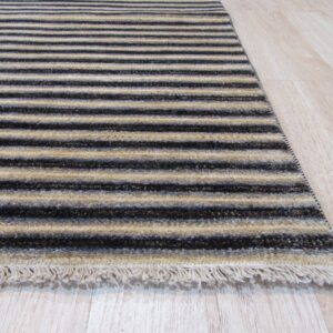 A textured rug runner with alternating dark and light beige stripes lies on blonde wood flooring.