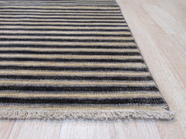 A textured rug runner with alternating dark and light beige stripes lies on blonde wood flooring.