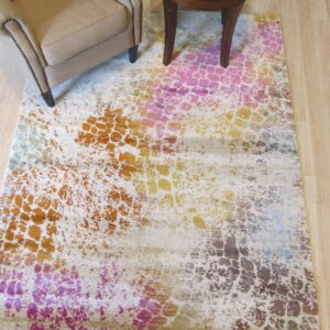Abstract rug in beige, pink, orange, and brown sits beneath a neutral armchair and dark wood side table.