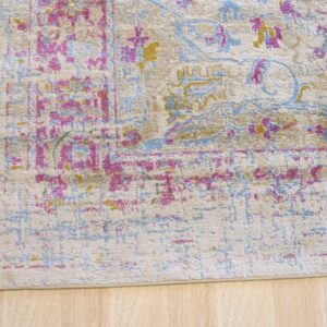 Distressed beige rug featuring traditional magenta, blue, and yellow patterns on light wood planks.