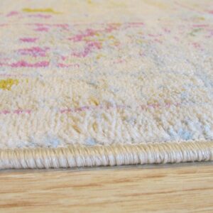 Cream low-pile rug with pink and yellow abstract pattern rests on wood flooring.