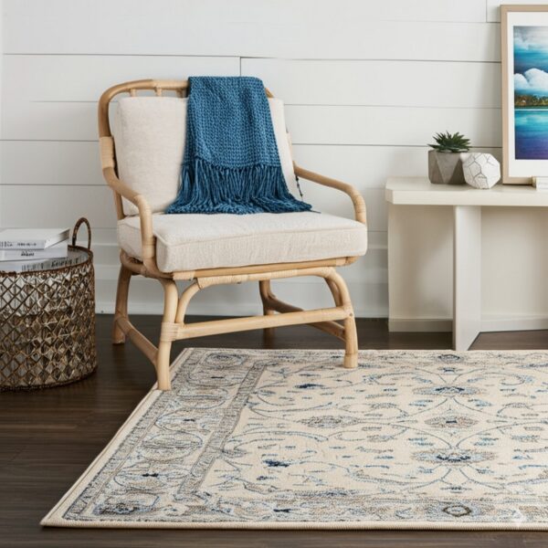 Cream and blue patterned rug anchors a space with dark wood floors and a natural rattan chair.