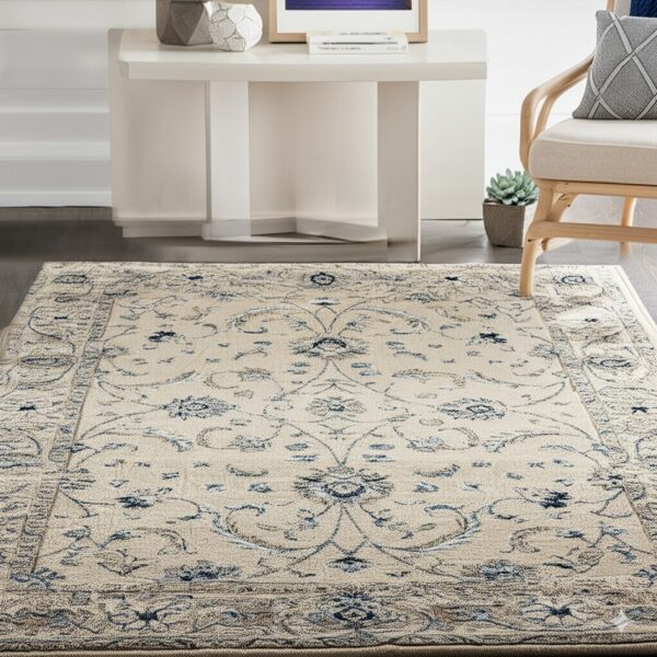 Cream rug with blue traditional floral patterns rests on dark flooring near a white table and wood chair.
