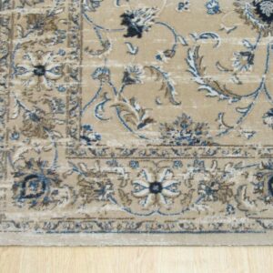 Traditional beige area rug with ornate blue, brown, and cream border rests on light planked wood.