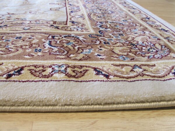 Medium-pile cream rug with a traditional brown and red border rests on light wood flooring.