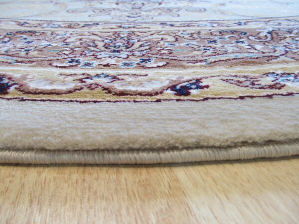 Ornate cream rug with red and blue accents, showing the pile edge resting on light wood flooring.