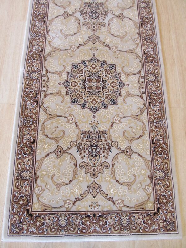 A beige runner rug with a traditional brown medallion pattern rests on light wood flooring.
