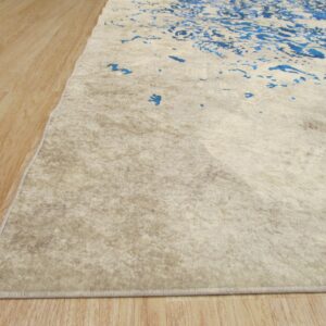 Low-pile rug in textured beige and blue abstract patterns rests on light wood-look flooring.